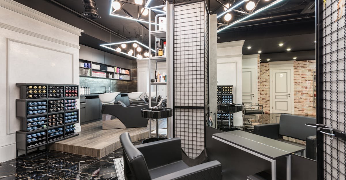 Black leather chair placed against mirror with reflection in stylish beauty salon with backwash chairs and abundance of cosmetology products